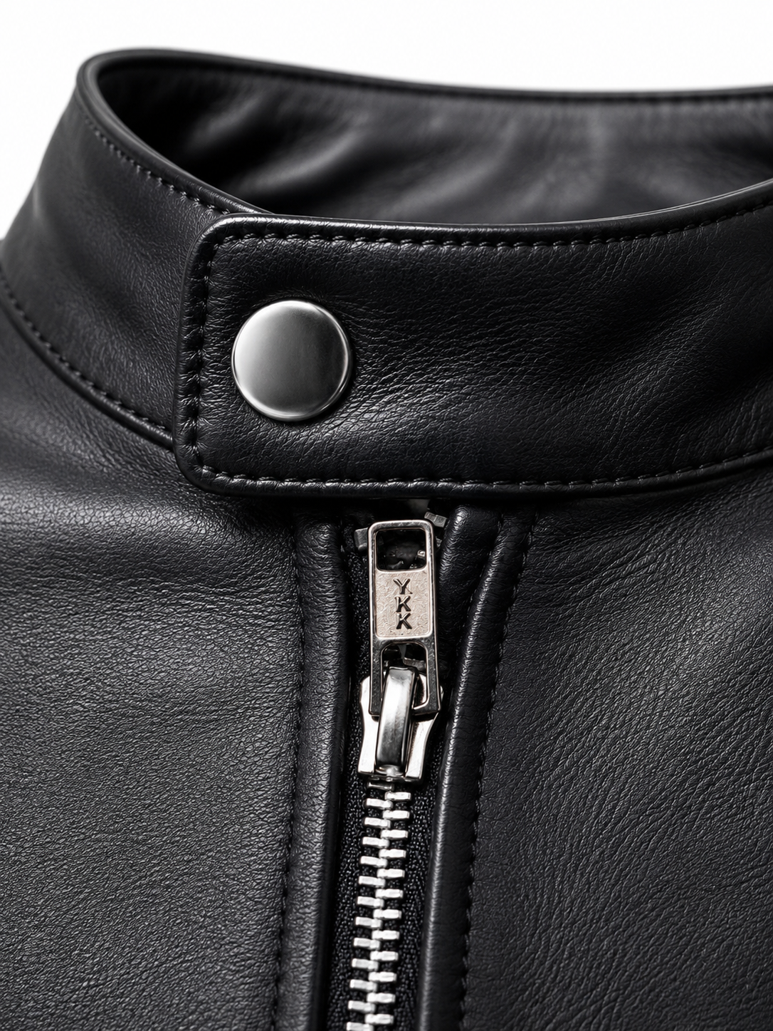 Close-up of a black leather jacket featuring a snap-button closure at the collar and a silver-toned front zipper with a visible YKK pull tab.