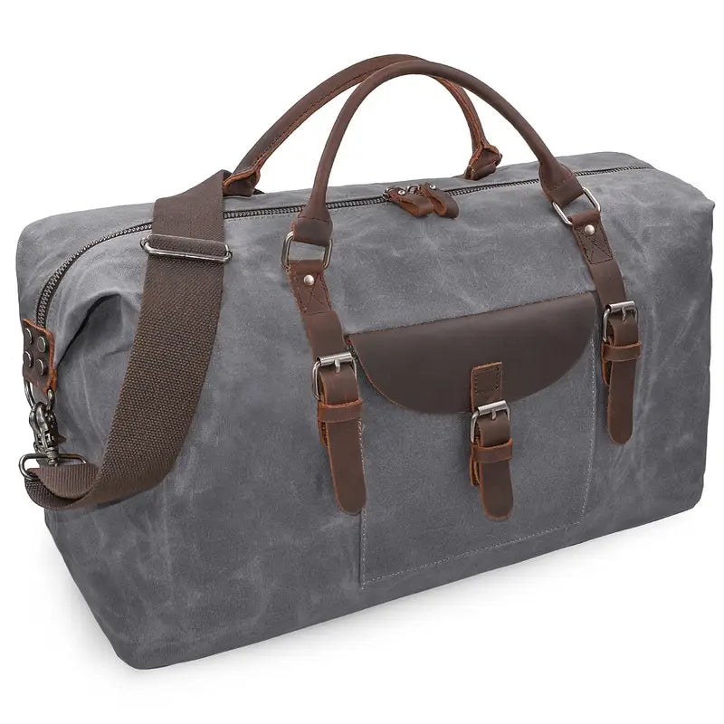 A brown waxed canvas and leather duffle bag with leather handles and a detachable leather shoulder strap, featuring metal hardware and heavy-duty zippers.