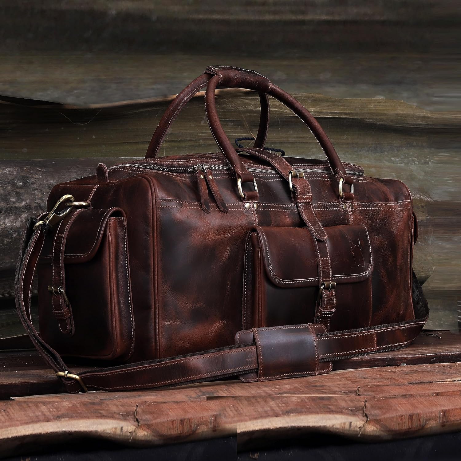 Brown leather duffel bag on a wooden surface with a blurred background