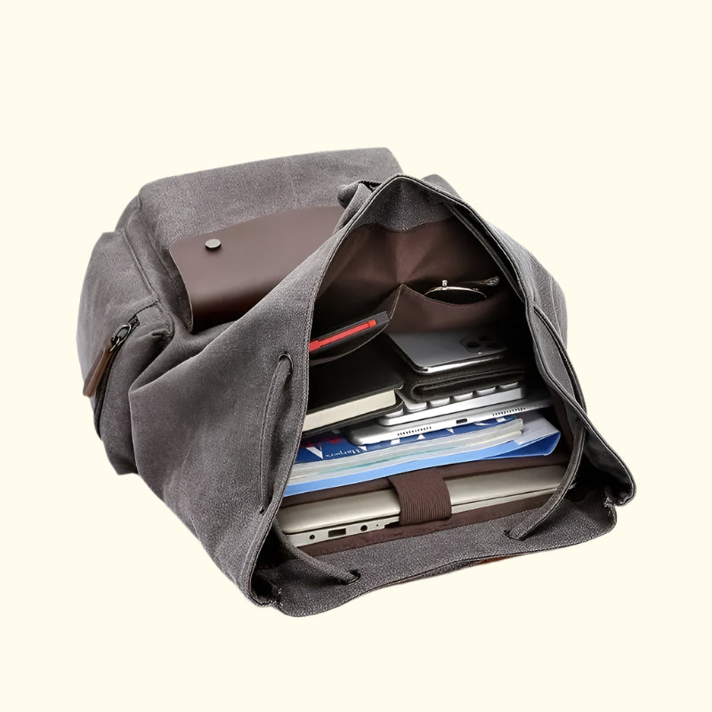 Gray backpack with compartments containing electronic devices on a white background