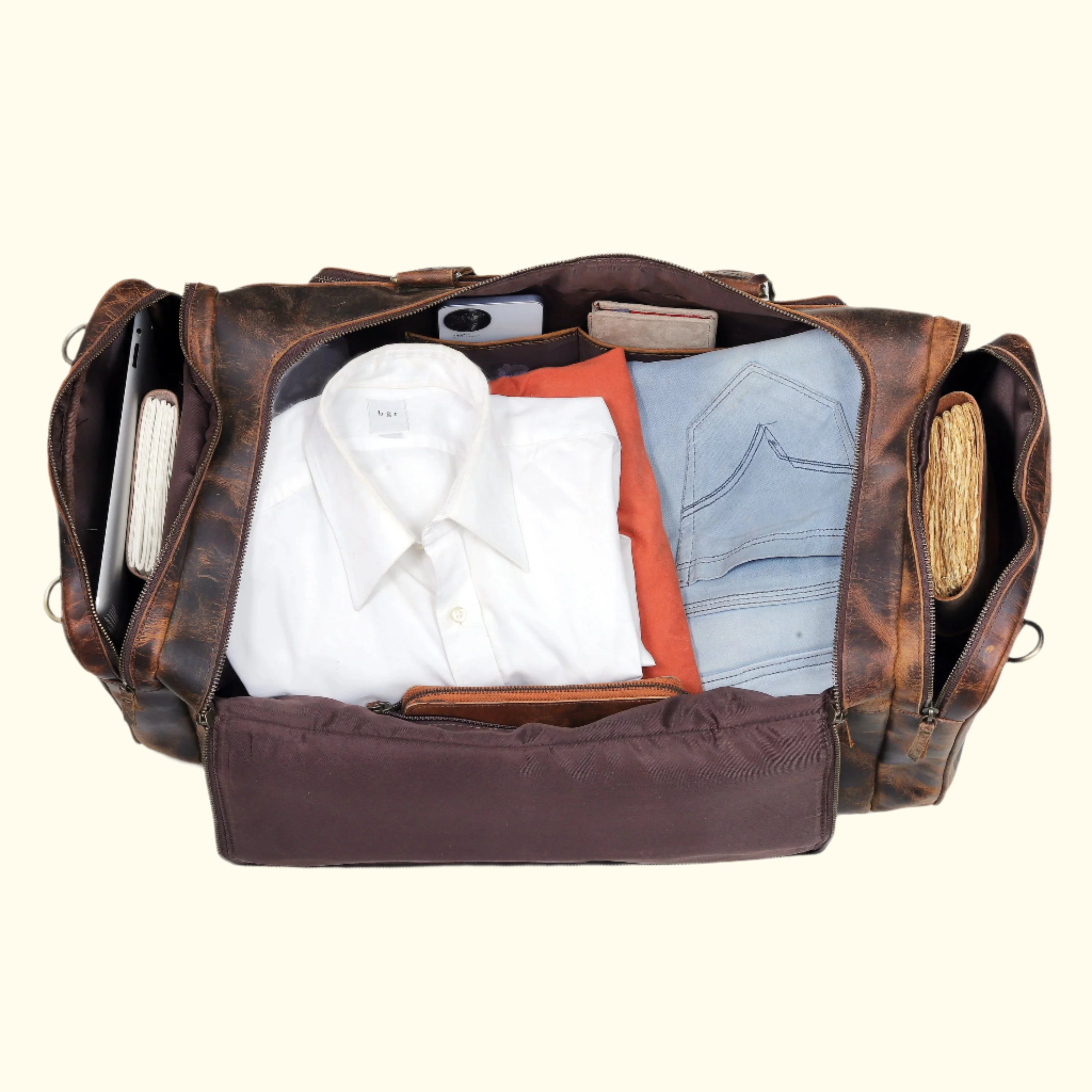 Brown leather duffel bag with clothes and items on a white background