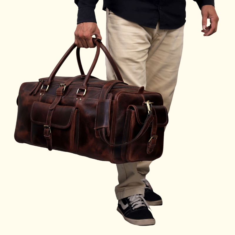 Person holding a large brown leather duffel bag against a plain background