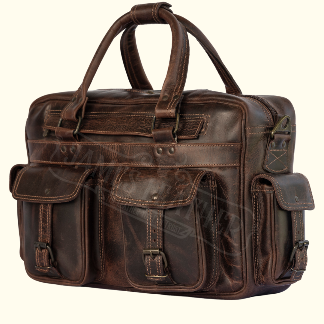 A vintage brown full-grain leather briefcase with brass buckles and a shoulder strap.