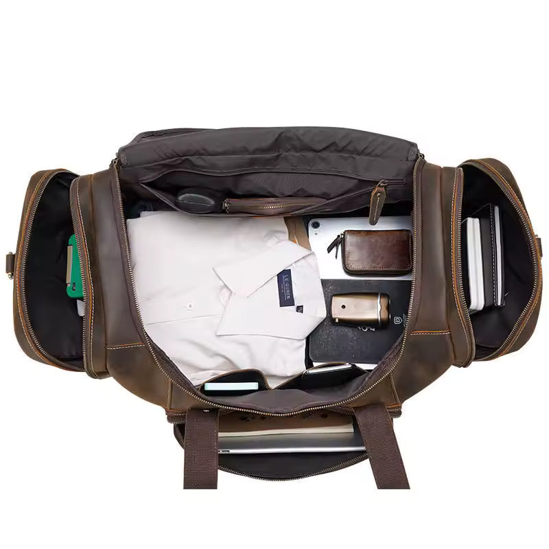 Open brown leather duffel bag with various items on a white background