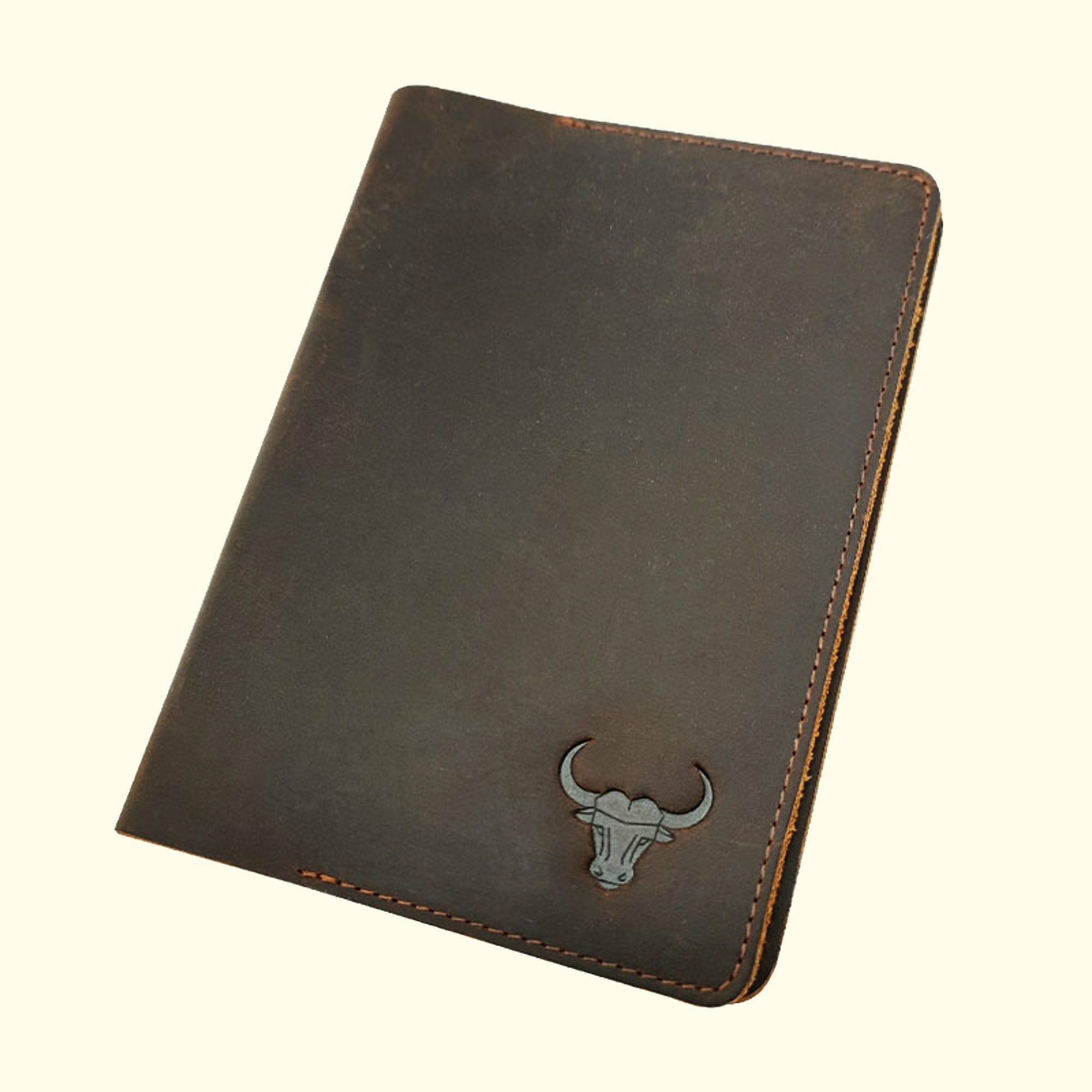 A brown vintage leather notebook holder with a bull's head embossed on it.
