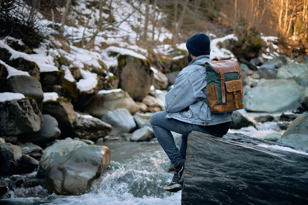 Person sitting on a stool in a forest with a backpack